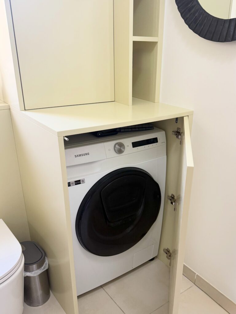 Lave-linge encastré dans un meuble, porte ouverte.