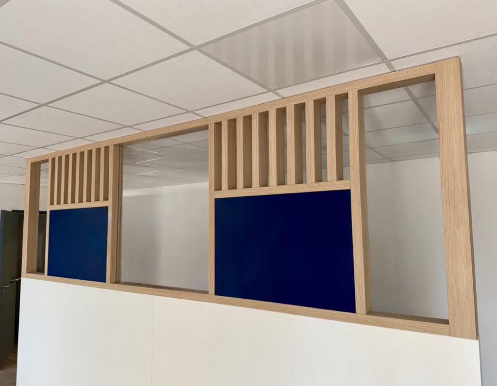 Cloison et agencement de laboratoire de biologie médicale design en bois avec panneaux bleus et lattes verticales sur mur blanc.