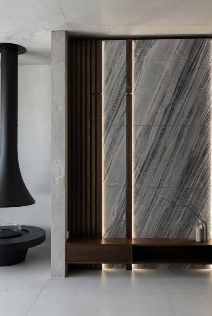 Mur d'accent moderne : pierre grise veinée, tasseaux bois sombre et éclairage LED intégré.